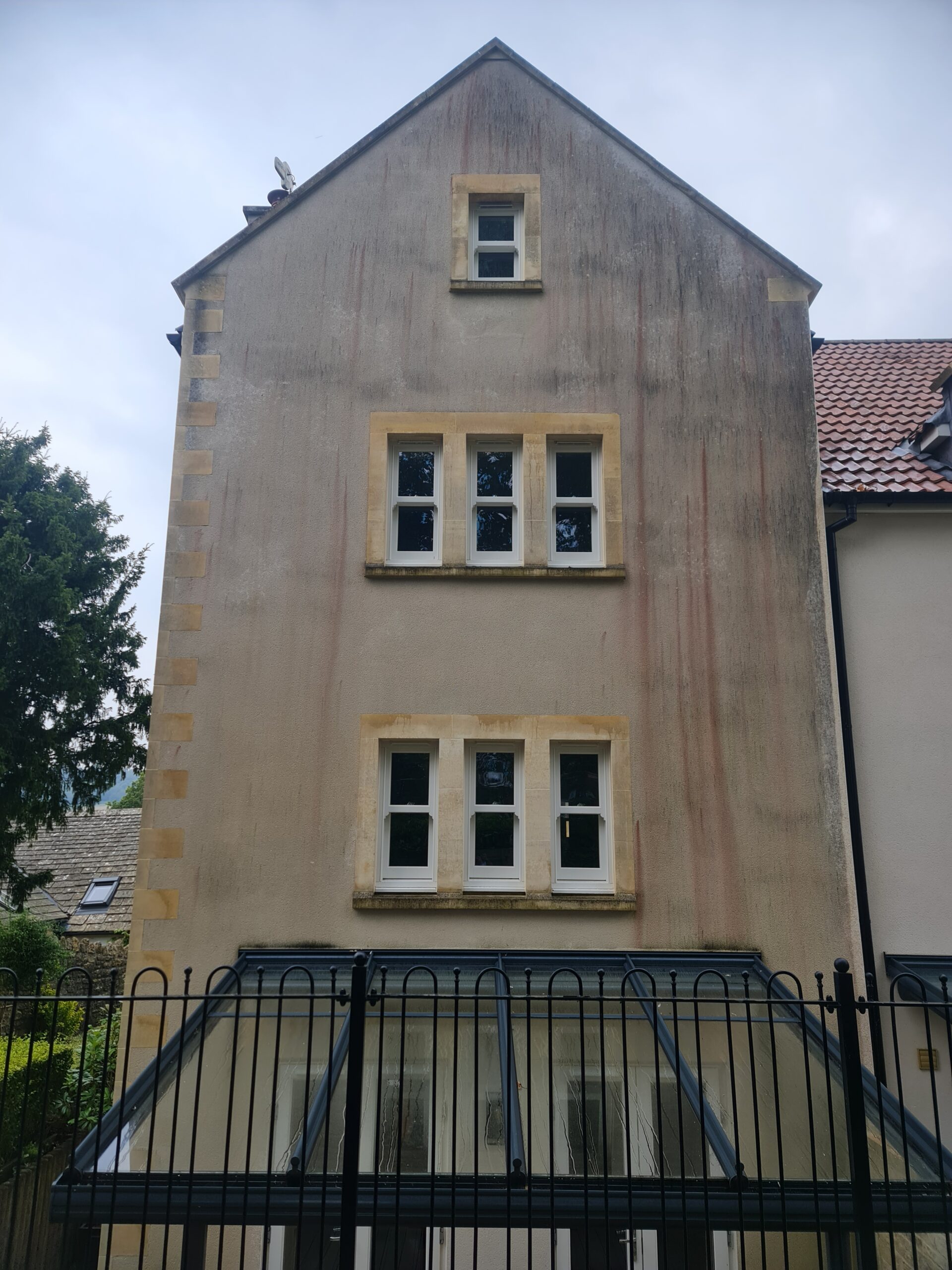 Rendered exterior covered in algae streaks and pollution staining before soft wash